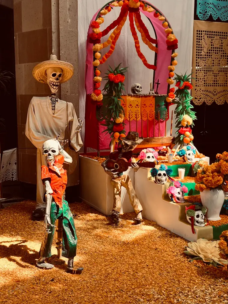 A Día de Muertos ofrenda with marigolds, papel picado, sugar skulls, and papier-mâché skeletons